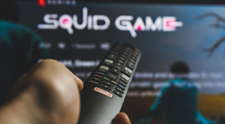 A photo of a person holding a remote pointing at the Netflix show "Squid Game"