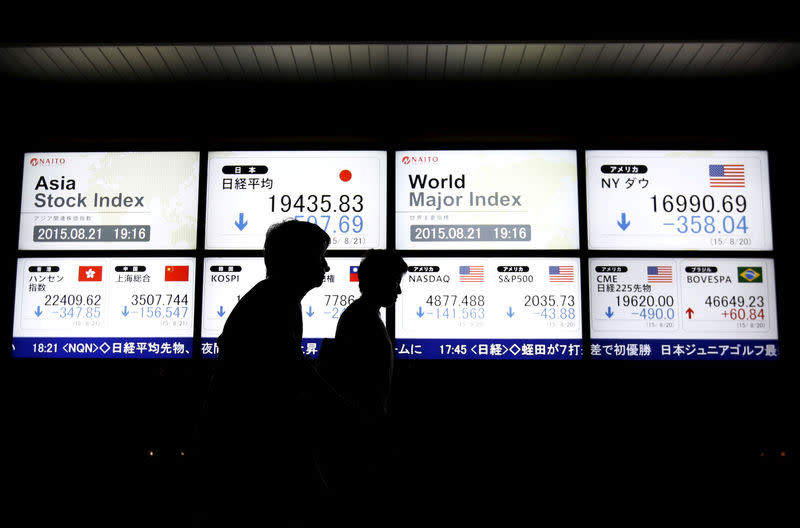 FILE PHOTO: People walk past an electronic board displaying various Asian countries' stock price index and world major index outside a brokerage in Tokyo, Japan, August 21, 2015. REUTERS/Issei Kato/File Photo