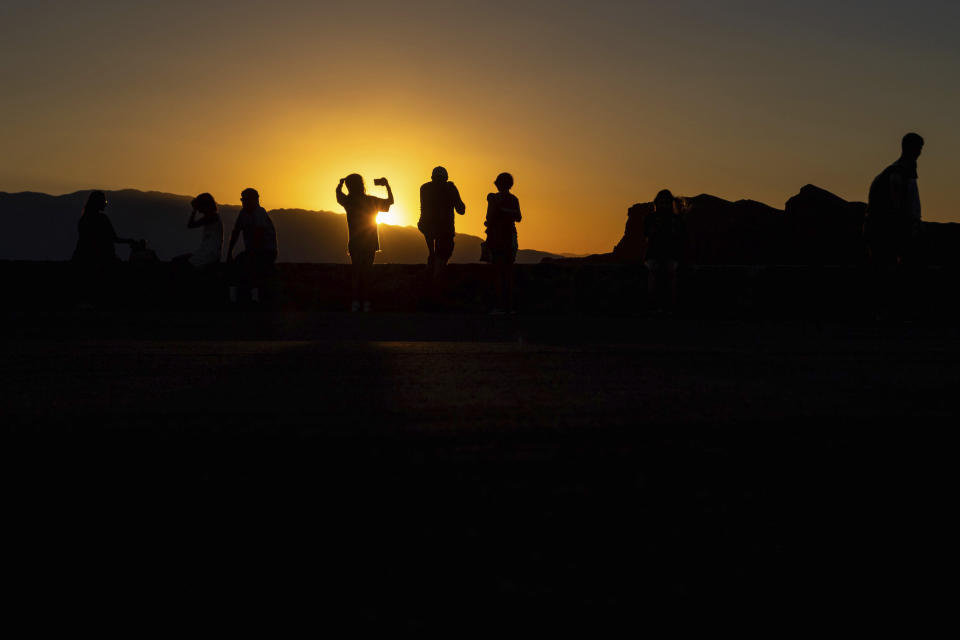 People enjoy a sunset at Zabriskie Point on Saturday, July 8, 2023, in Death Valley National Park, Calif. July is the hottest month at the park with an average high of 116 degrees (46.5 Celsius). (AP Photo/Ty ONeil)