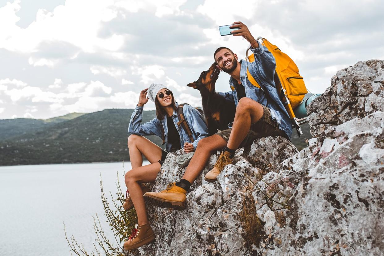 doberman sitting on large rock with man and woman after hiking