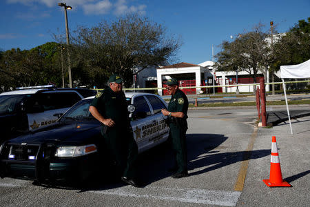 FILE PHOTO: Police officers Jamie Rubenstein (C) and Brad Griesinger talk as they stand guard in front of the Marjory Stoneman Douglas High School, after the police security perimeter was removed following a mass shooting, in Parkland, Florida, U.S., February 18, 2018. REUTERS/Carlos Garcia Rawlins/File Photo