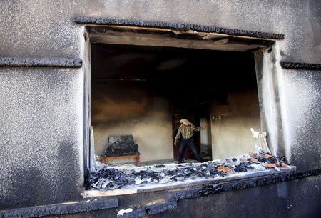 A Palestinian man inspects a house that was badly damaged in a suspected attack by Jewish extremists on two houses at Duma village near the West Bank city of Nablus July 31, 2015. REUTERS/Abed Omar Qusini