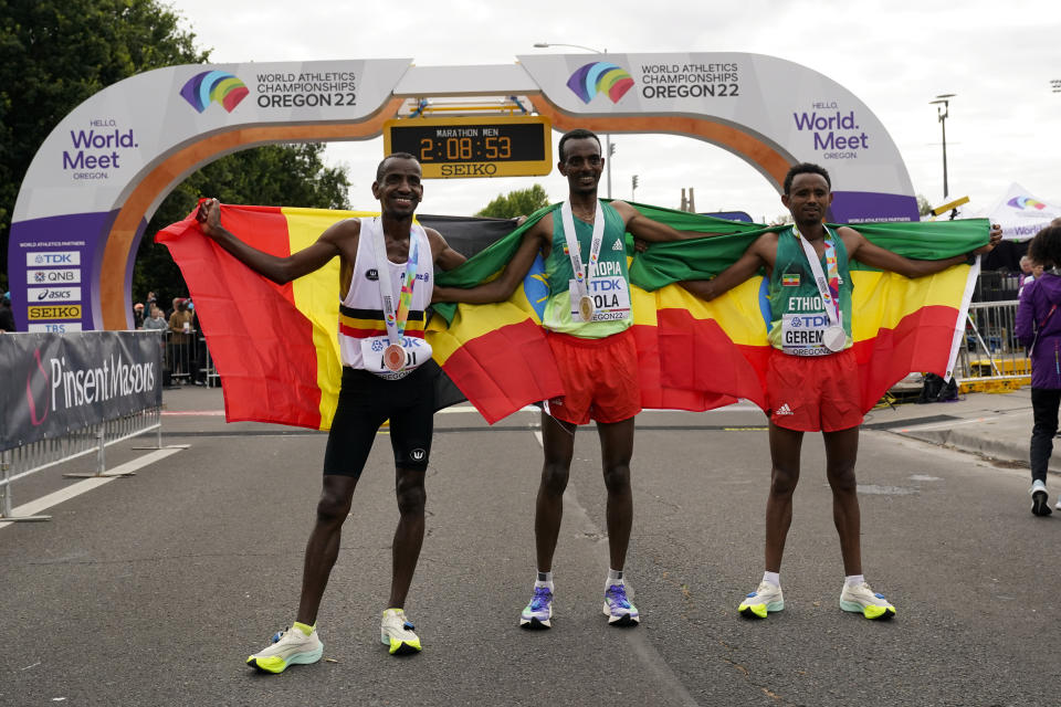 Gold medalist Tamirat Tola, of Ethiopia, center, stands with silver medalist Mosinet Geremew, of Ethiopia, right, and bronze medalist Bashir Abdi, of Belgium, after the men's marathon at the World Athletics Championships on Sunday, July 17, 2022, in Eugene, Ore. (AP Photo/Gregory Bull)