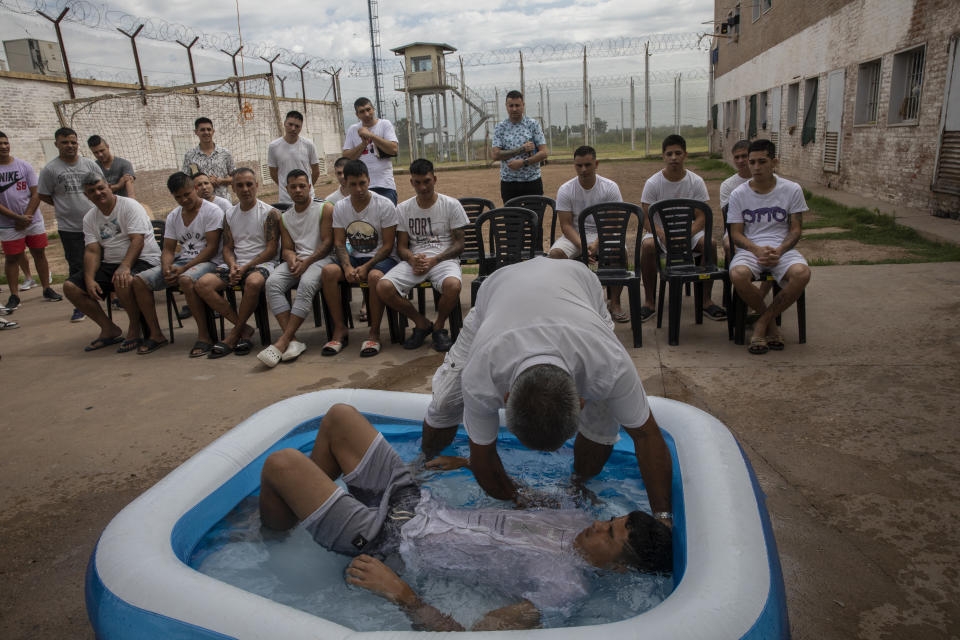 Ruben Munoz, an evangelical pastor from the church Puerta del Cielo, or "Heaven's Door," who served two years in prison for robbery, baptizes an inmate in a kiddie pool, at an evangelical cellblock inside Penal Unit N11 in Pinero, Santa Fe province, Argentina, Saturday, Dec. 11, 2021. Over the past 20 years, Argentine prison authorities have encouraged the creation of units effectively run by evangelical inmates. (AP Photo/Rodrigo Abd)