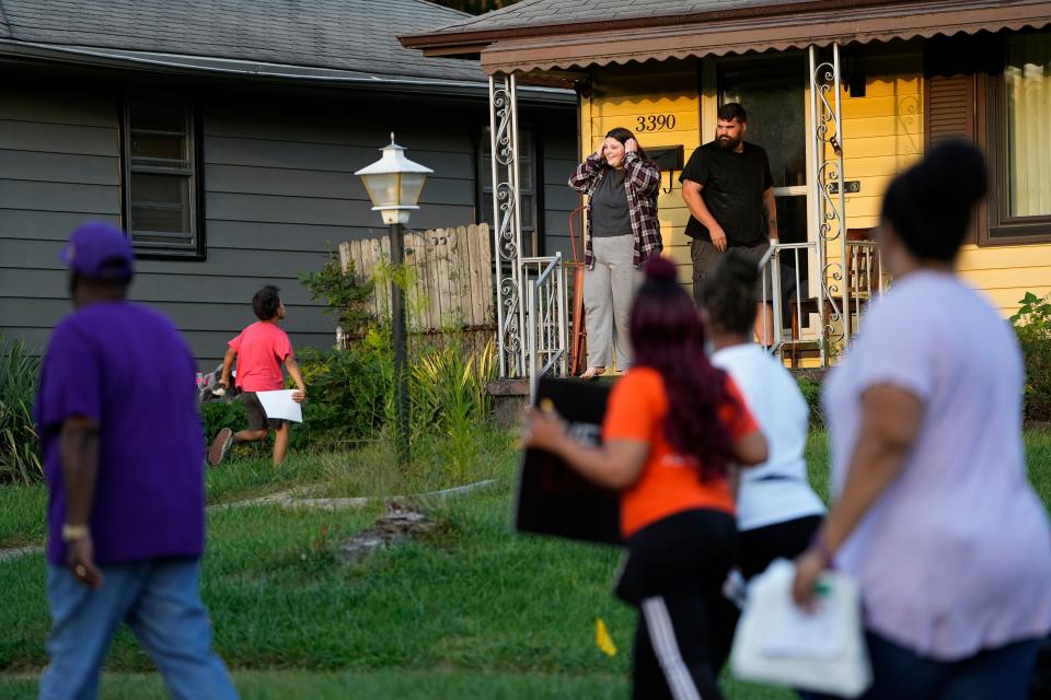 Madelaine Smith, 25, and her brother, Avery Smith, 29, step outside on their porch as a group hoping to combat gun violence walks through the neighborhood.
