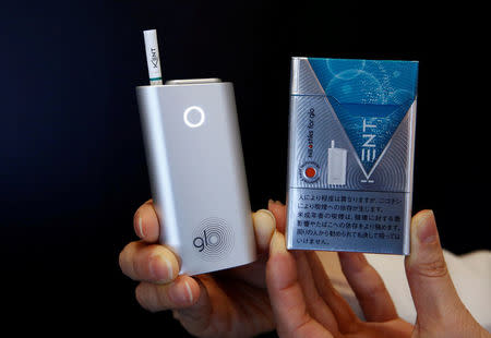 FILE PHOTO: A promoter shows British American Tobacco's new tobacco heating system device 'glo' (L) and Kent tobacco after a news conference in Tokyo, Japan, November 8, 2016. REUTERS/Kim Kyung-Hoon/File Photo