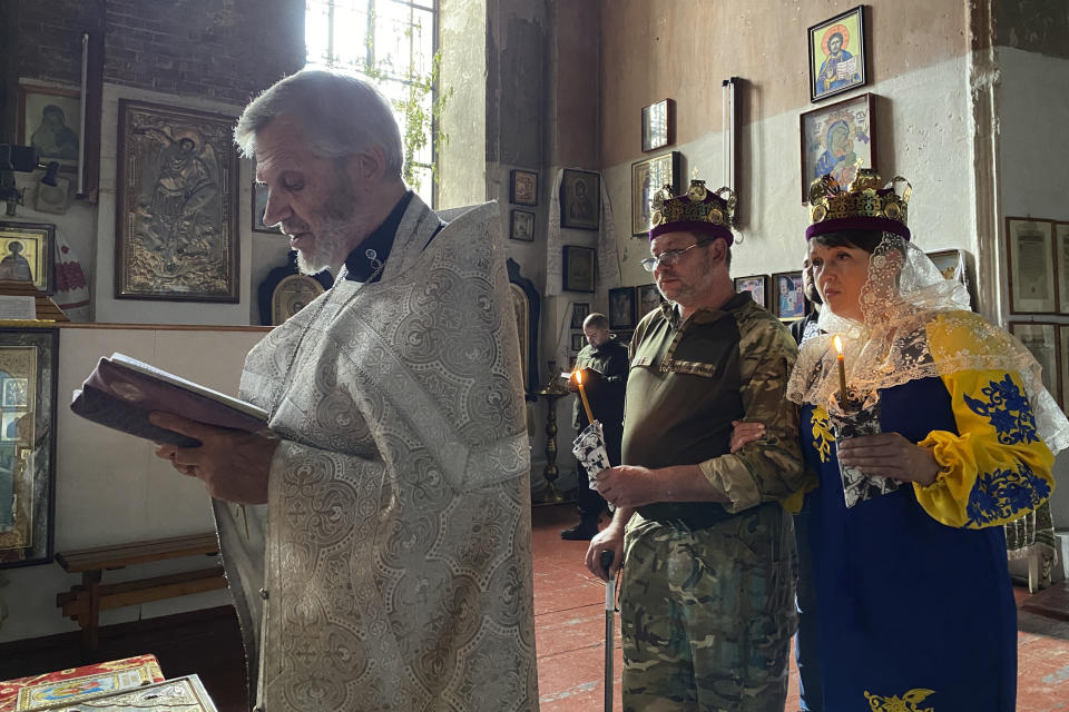 Olena Yahupova stands with her husband, Arthur Yahupov during their June 7, 2023 wedding ceremony in Kharkiv, Ukraine. After escaping detention by Russian soldiers, she traveled thousands of miles through Russia, north to the Baltics and back around to the frontline in Ukraine, where she reunited with her husband serving with Ukrainian forces. Earlier married in a civil ceremony, the two got wed in church. (AP Photo/.Oleksandr Brynza)