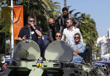 (2ndL-R) Cast members Randy Couture, Arnold Schwarzenegger, Victor Ortiz, Glen Powell and Antonio Banderas pose on a tank as they arrive on the Croisette to promote the film "The Expendables 3" during the 67th Cannes Film Festival in Cannes May 18, 2014. REUTERS/Yves Herman