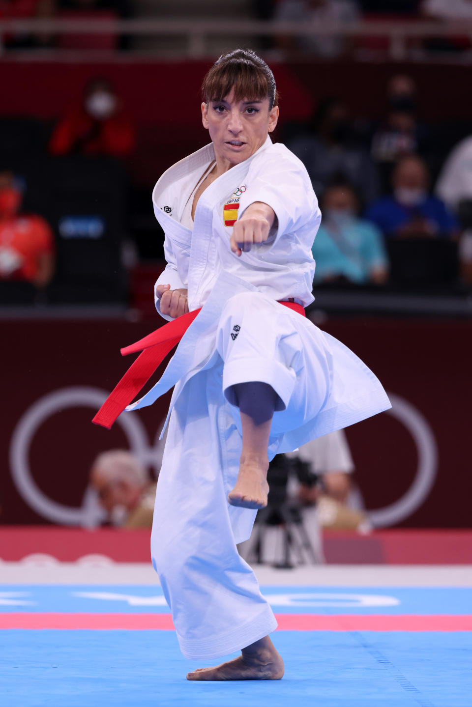 Sandra Sánchez performs a karate move in a martial arts uniform with a red belt at a competition