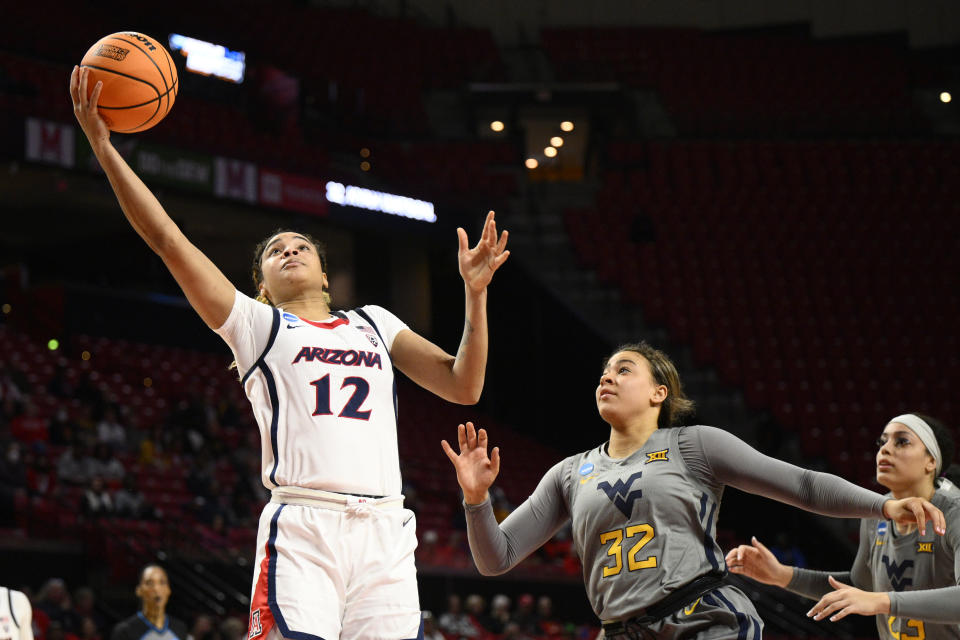 Arizona forward Esmery Martinez (12) goes to the basket past West Virginia guard Kyah Watson (32) and forward Isis Beh, right, in the first half of a first-round college basketball game in the NCAA Tournament, Friday, March 17, 2023, in College Park, Md. (AP Photo/Nick Wass)