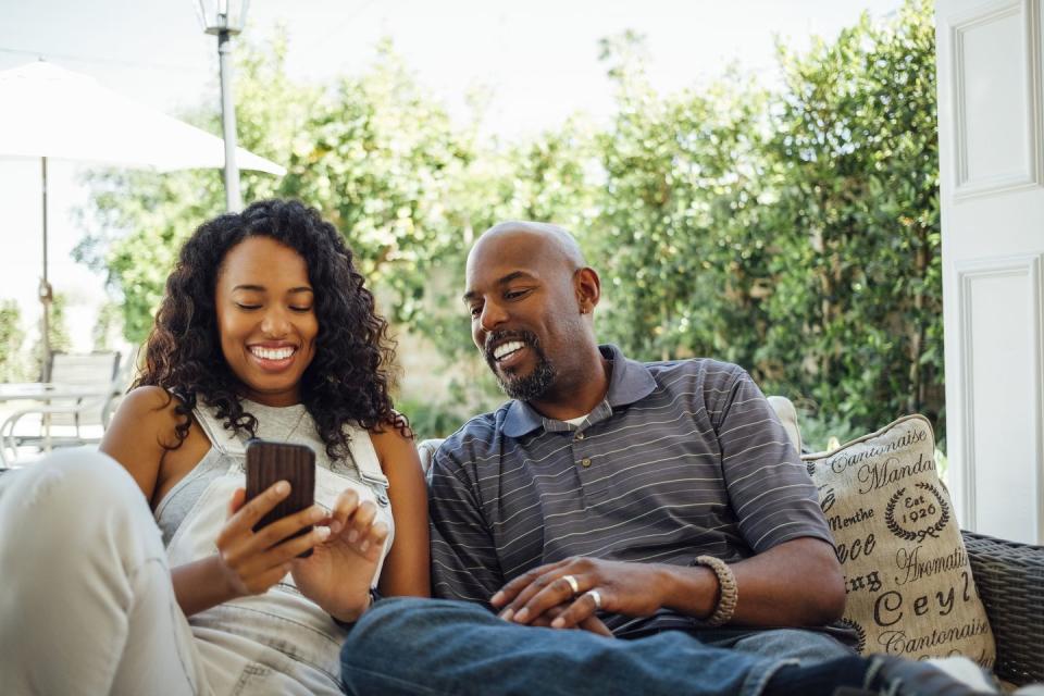 adult siblings looking at smart phone together in backyard