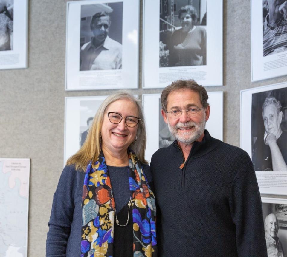 Barbara Harvis and Andrew Renny stand below photos of Andrew’s parents, Marcell and Catherine Renny, Holocaust survivors whose stories are included in the archives of the Sara and Sam Schoffer Holocaust Resource Center at Stockton University.