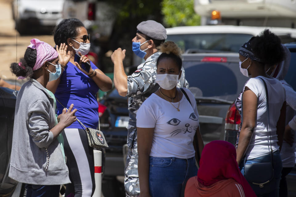 An Ethiopian domestic worker argues with a Lebanese policeman as dozens of Ethiopian workers gather outside the Ethiopian consulate, some inquiring about flights home, others stranded after they were abandoned by employers who claimed they could no longer afford to pay their salaries, in Hazmieh, east of Beirut, Lebanon, Thursday, June 4, 2020. Some 180,000 domestic workers in Lebanon, most of them female from Ethiopia, are growing more desperate as a crippling economic and financial crisis sets in, coupled with coronavirus restrictions. (AP Photo/Hassan Ammar)