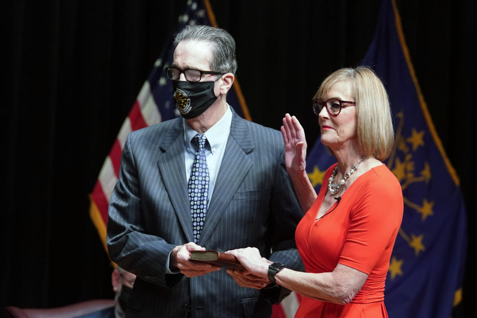 FILE - Suzanne Crouch is sworn in as Indiana's lieutenant governor by Chief Justice Loretta H. Rush on a Bible held by her husband, Larry Downs, during an inaugural ceremony at the Indiana State Museum, Monday, Jan. 11, 2021, in Indianapolis. Crouch formally started her 2024 campaign for governor on Monday, Dec. 12, 2022, and said she would not shy away from Republican Gov. Eric Holcomb's record despite discontent among many conservatives over his COVID-19 policies and other actions. (AP Photo/Darron Cummings, File)