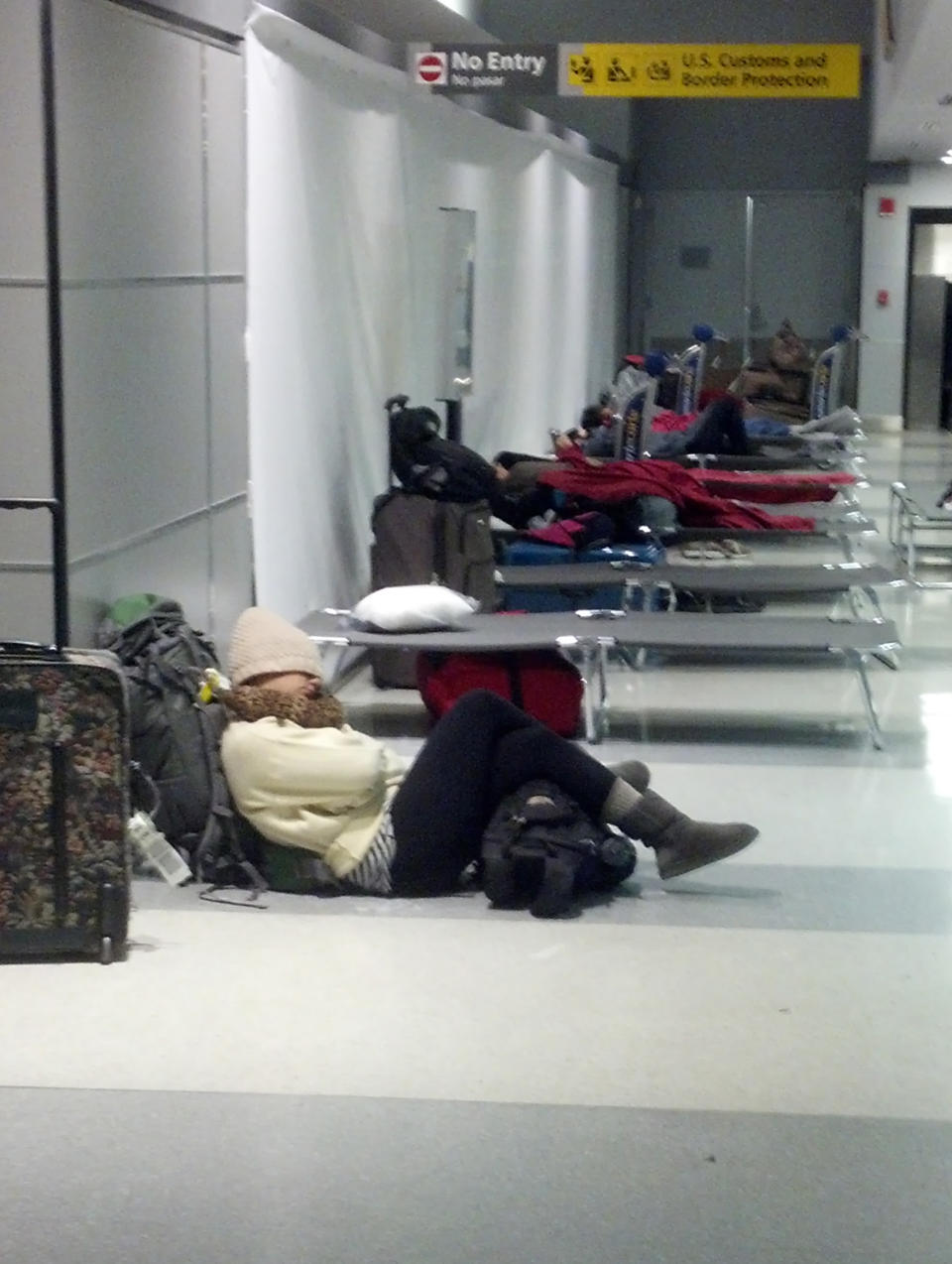 In this photo provided by Jeremy J. Shapiro, passengers stranded at New York's JFK International Airport rest on cots in a hallway of American Airlines' Terminal 8 on Friday, Jan. 3, 2014, after their flight plans were interrupted by a winter storm. Hundreds of flights were canceled at New York’s three major airports due to poor visibility and blowing snow. (AP Photo/Jeremy J. Shapiro)