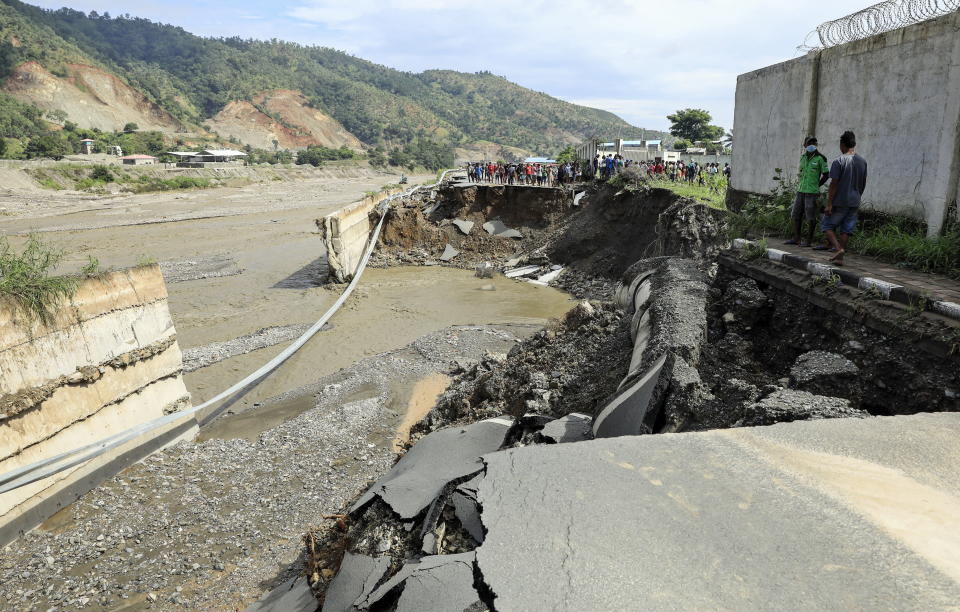 People gather near a damaged road in the aftermath of floods in Dili, East Timor, also known as Timor Leste.