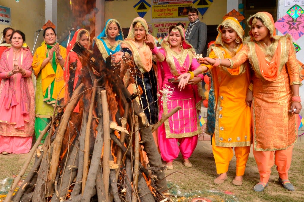 Students wearing traditional Punjabi outfits perform a ritual around a bonfire to celebrate Lohri (AFP via Getty Images)