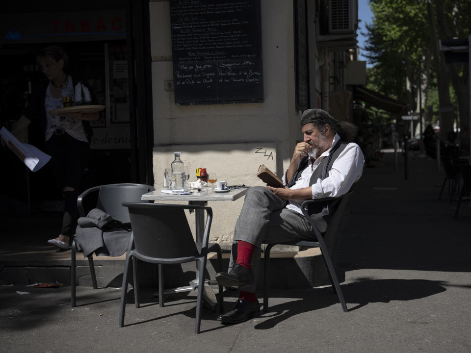 A man reads a book at a cafe in Marseille, southern France, Saturday, April 20, 2024. (AP Photo/Daniel Cole)