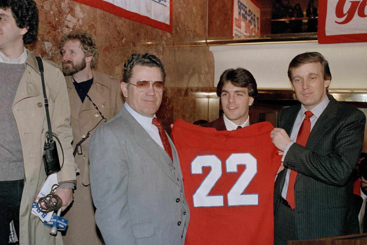 Boston College quarterback Doug Flutie poses with New Jersey Generals head coach Walt Michaels, left, and General's owner, Donald Trump, at a news conference in New York, on Feb. 5, 1985. An official announcement was made that Flutie signed a multi-million-dollar pact with the USFL team.