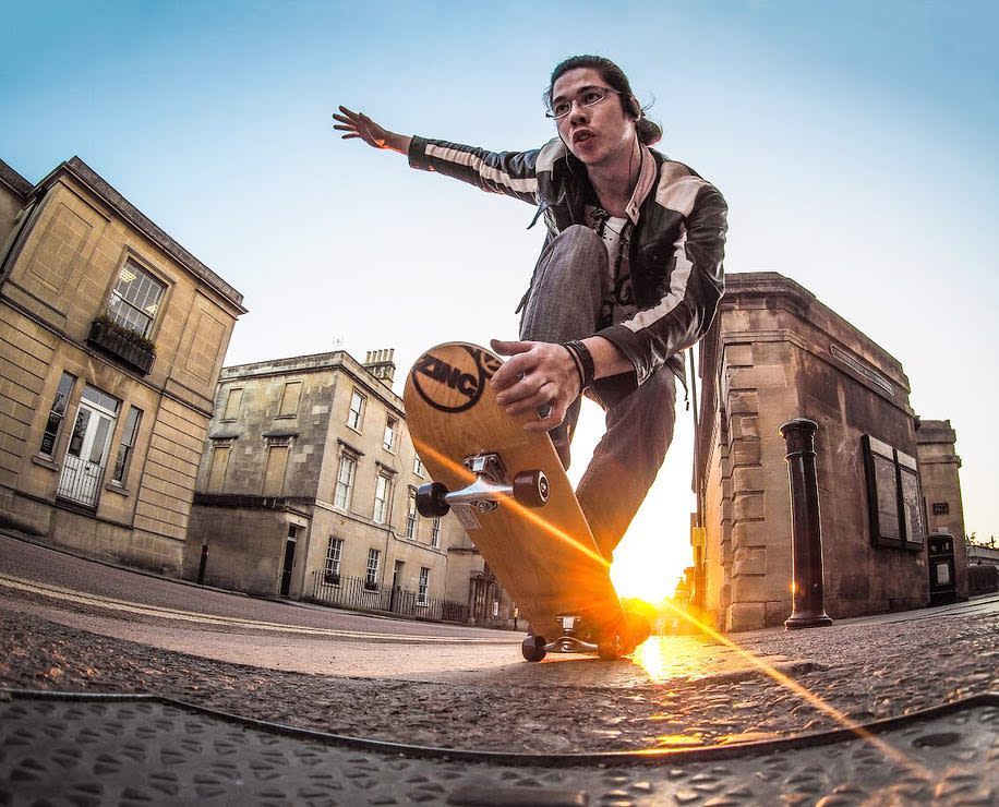 Olympus 9mm body cap image of a skateboarder skating down a street at sunset