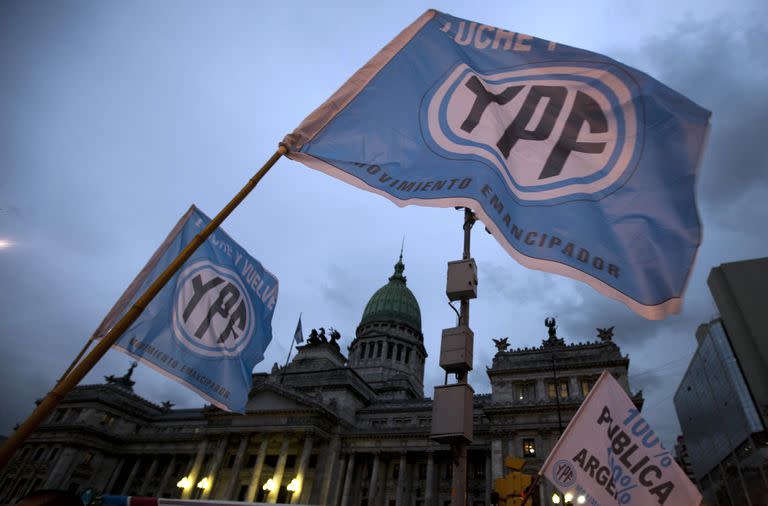 ARCHIVO - Seguidores a favor de la propuesta de nacionalizar la petrolera YPF de la presidenta de Argentina, Cristina Fernéndez, ondeaban banderas a las afueras del Congreso en Buenos Aires, Argentina. Una corte de Nueva York condenó a Argentina, en una resolución que se dio a conocer el viernes 31 de marzo de 2023, por la expropiación de la petrolera YPF en 2012 y ordenó una compensación económica para los accionistas afectados. (AP Foto/Natacha Pisarenko, Archivo)