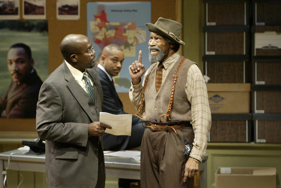 James A. Williams, front left, as Roosevelt Hicks, Anthony Chisholm, as Elder Joseph Barlow, right, and Rocky Carroll cq, as Harmond Wilks, sitting on desk, acting for set up media photos of the West Coast premiere of Radio Golf. (Photo by Ricardo DeAratanha/Los Angeles Times via Getty Images)