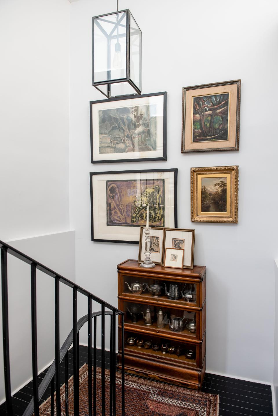 A vignette in the staircase leading to the third floor showcases a wooden curio, locally sourced from an antique shop and filled with a collection of silver-plated teapots. Above, a collection of paintings found in various European flea markets can be seen.