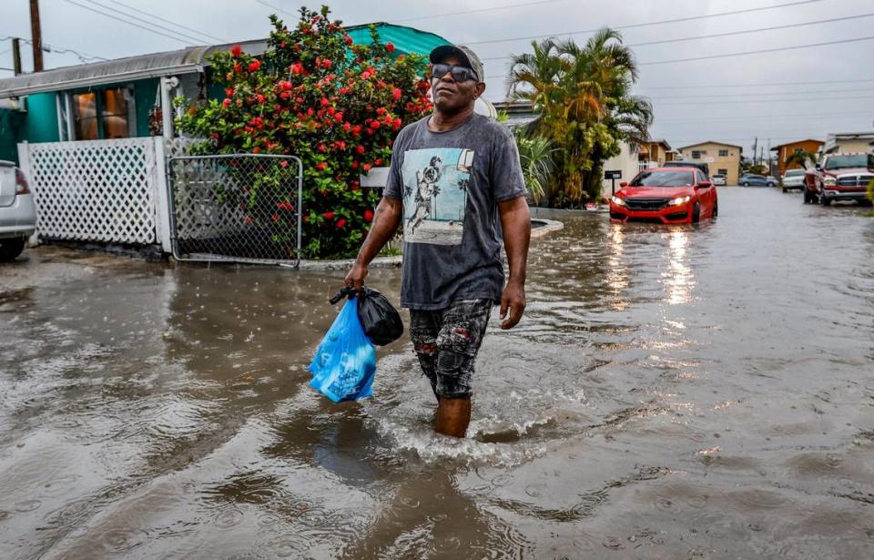 Mires Aguenar walks through a flooded street at Holiday Acres Mobile Home Park in Hialeah, Florida, on Wednesday, June 12, 2024.