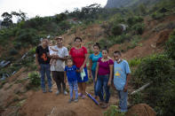 From left, Melvin Alonso, 14; Guillermo Alonso, 54; Elvin Alonso, 6 months; Maria Orellana, 52; Genesis Alonso, 6; Yenny Alonso, 16; Areli Alonso, 22, and Orlin Alonso, 25, stand for a photo at the site where their home was destroyed by a landslide triggered by hurricanes Eta and Iota in the village of La Reina, Honduras, Thursday, June 24, 2021. "We feel sad because we are homeless, but the important thing is that the whole family is alive," says Guillermo. (AP Photo/Rodrigo Abd)