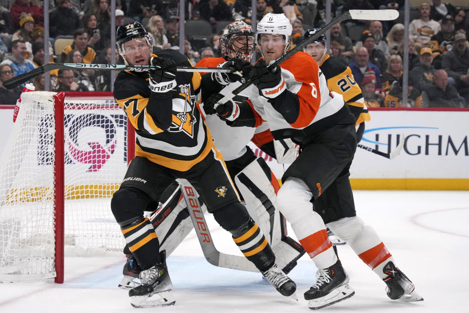 Pittsburgh Penguins' Jeff Carter (77) works to screen Philadelphia Flyers goaltender Samuel Ersson, second from left, with Flyers' Cam York (8) defending during the second period of an NHL hockey game in Pittsburgh, Saturday, Dec. 2, 2023. (AP Photo/Gene J. Puskar)