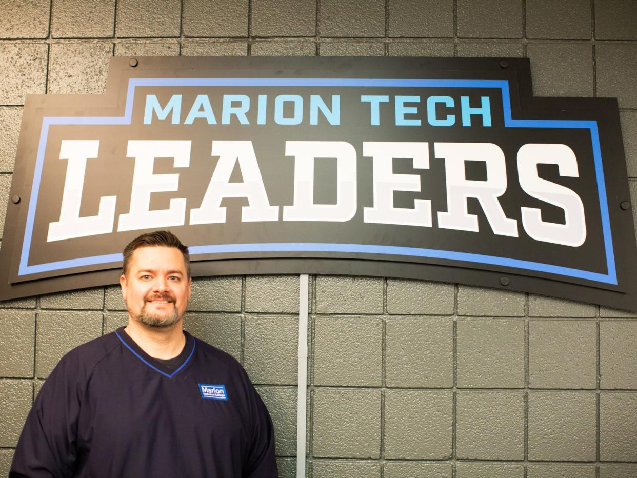 Justin Dean from Marion Tech is shown in front a new sign that he designed for the school's upcoming Esports program.