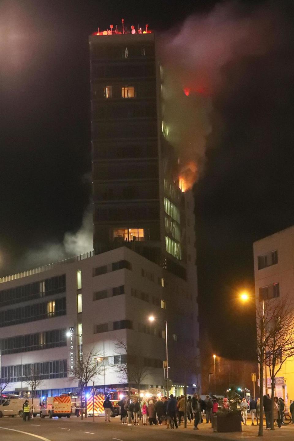 People watch the flames from the foot of the Metro Hotel (PA)