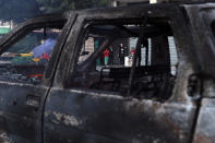 A family look at a burning car after heavy clashes in the coastal town of Khaldeh, south of Beirut, Lebanon, Sunday, Aug. 1, 2021. At least two people were killed on Sunday south of the Lebanese capital when gunmen opened fire at the funeral of a Hezbollah commander who was killed a day earlier, an official from the group said. (AP Photo/Bilal Hussein)