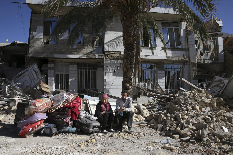 <p>Survivors sit in front of a destroyed house on the earthquake site in Sarpol-e-Zahab in western Iran, Nov. 14, 2017. Rescuers are digging through the debris of buildings felled by the Sunday earthquake in the border region of Iran and Iraq. (Photo: Vahid Salemi/AP) </p>