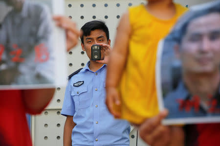 A police officer films family members of those detained in what is known as the "709" crackdown protesting in front of the Supreme People's Procuratorate in Beijing, China July 7, 2017. REUTERS/Damir Sagolj