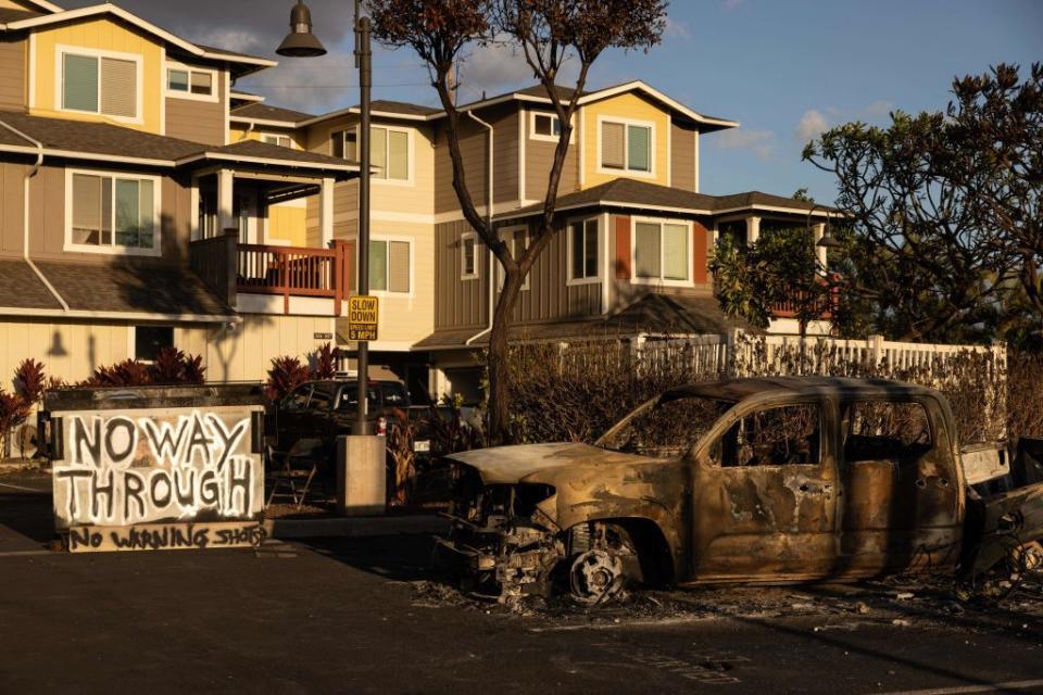 A burnt out car and a sign reading 