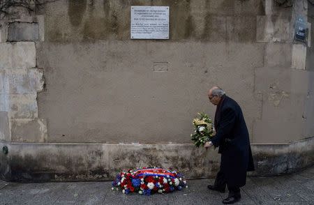 A man pays respects under a commemorative plaque unveiled by French President Francois Hollande and Paris Mayor Anne Hidalgo next to the "Le Carillon" and "Le Petit Cambodge" bars and restaurants, in Paris, France, November 13, 2016, during a ceremony held for the victims of last year's Paris attacks which targeted the Bataclan concert hall as well as a series of bars and killed 130 people. REUTERS/Christophe Petit Tesson/Pool