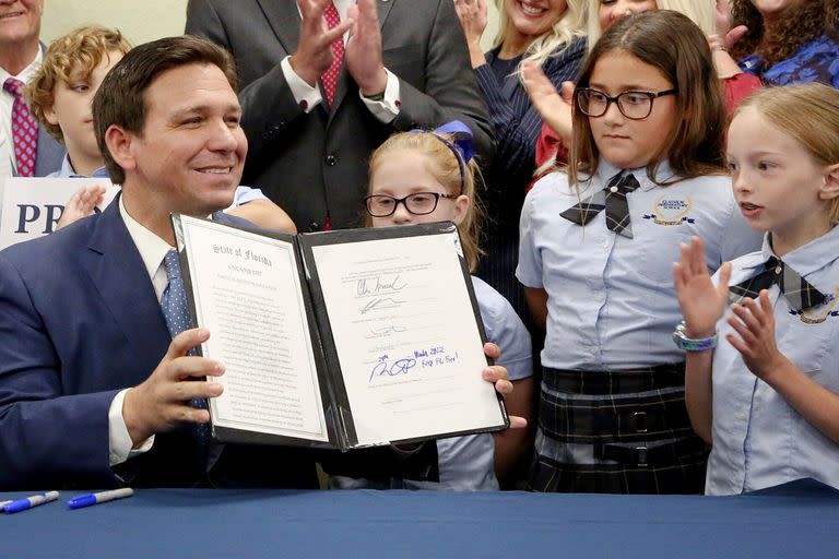 El gobernador de la Florida Ron DeSantis muestra la firma que estampó en una ley sobre los derechos de los padres en el campo de la educación, que sus detractores describen como la ley del "No Digas Gay". Foto del 28 de marzo del 2022 en Shady Hills (Florida). (Douglas R. Clifford/Tampa Bay Times via AP)