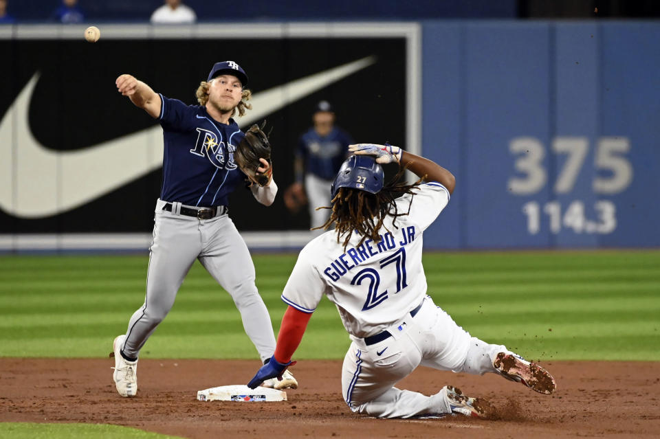 Tampa Bay Rays second baseman Taylor Walls, left, throws to first base to complete a double play on Toronto Blue Jays Bo Bichette after forcing Vladimir Guerrero Jr (27) at second base in the first inning of the first baseball game of a doubleheader in Toronto, Tuesday, Sept. 13, 2022. (Jon Blacker/The Canadian Press via AP)