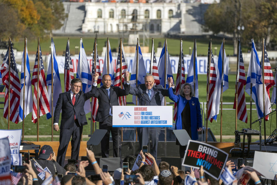 Desde la izquierda, el presidente de la Cámara de Representantes, Mike Johnson, el líder de la minoría en la cámara baja, Hakeem Jeffries, el líder de la mayoría en el Senado, Chuck Schumer y la senadora Joni Ernst, se toman de las manos durante la Marcha por Israel, el martes 14 de noviembre de 2023, en el parque de monumentos nacionales National Mall, en Washington. (AP Foto/Mark Schiefelbein)