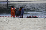 Workers clean oil spill along Sentosa's Tanjong Beach area in Singapore, Sunday, June 16, 2024. An oil spill caused by a dredger boat hitting a stationary cargo tanker has blackened part of Singapore’s southern coastline, including the popular resort island of Sentosa, and sparked concerns it may threaten marine wildlife. (AP Photo/Suhaimi Abdullah)