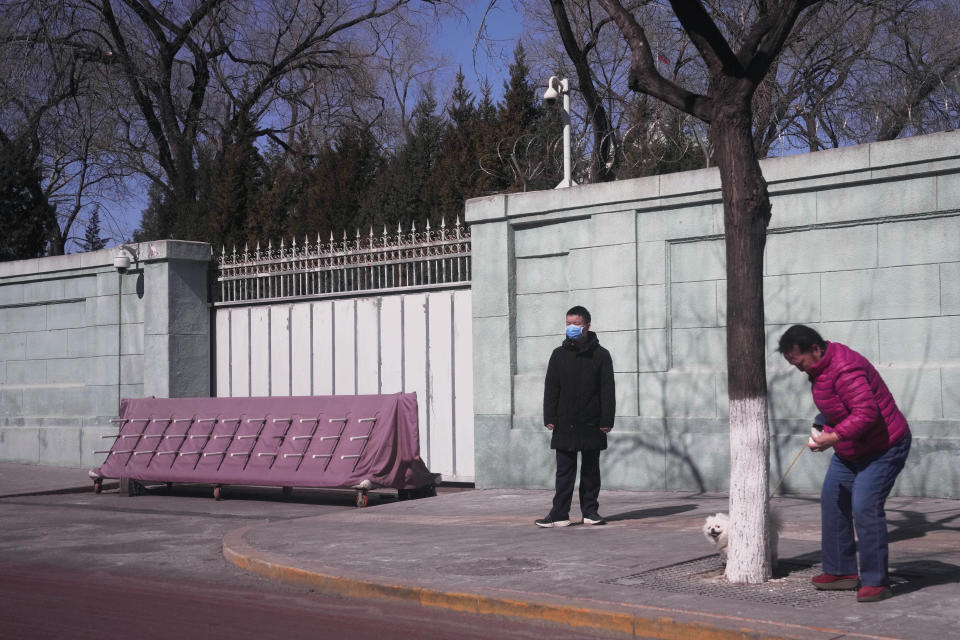 A resident walks her dog near a plainclothes security person standing watch outside the Russian Embassy in Beijing on Tuesday, March 1, 2022. As the West condemns Russia, President Vladimir Putin has vocal supporters in China, where the ruling Communist Party tells its people they are a fellow target of U.S.-led harassment. Public sentiment largely reflects the stance of a ruling party that is the closest thing Putin has to a major ally: The war should stop but the United States is to blame. (AP Photo/Ng Han Guan)