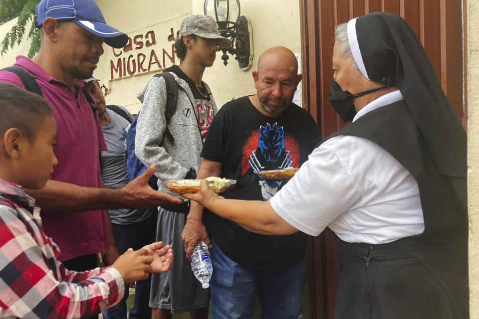 Isabel Turcios, director of the Casa del Migrante migrant services center delivers breakfasts of rice, beans and tortillas to migrants lined up outside, June 1, 2022 in Piedras Negras, Mexico. (AP Photo/Elliot Spagat)