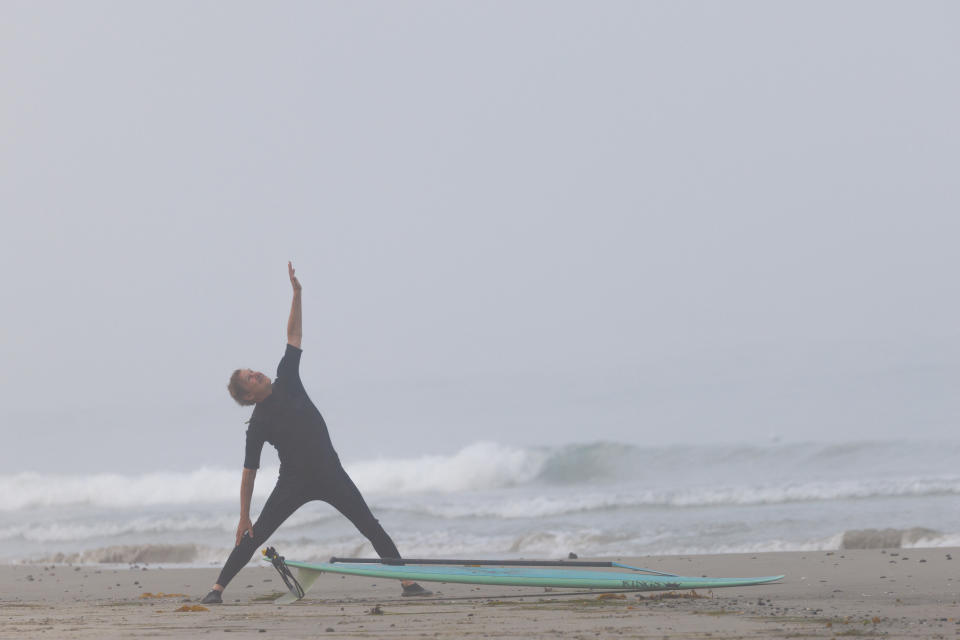 Surfer Stuart Grauer stretches his body before going out to surf, at Cardiff State Beach in Encinitas, California, U.S., July 26, 2023. REUTERS/Mike Blake