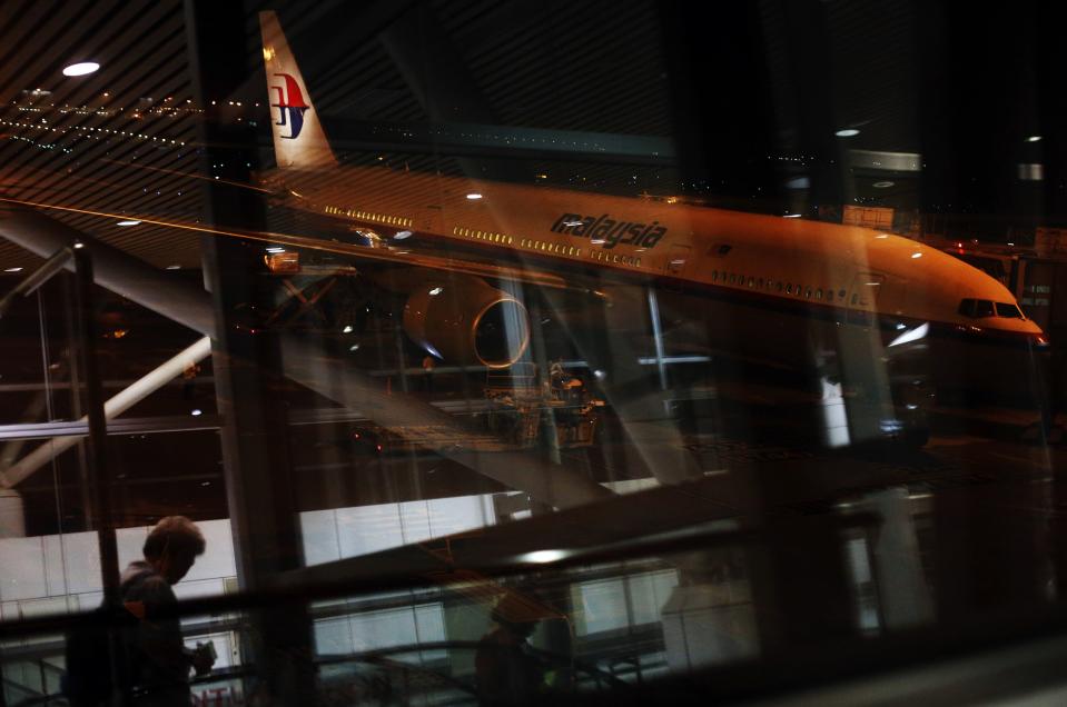 A Malaysia Airlines Boeing 777-200ER flight MH318 to Beijing sits on the tarmac as passengers are reflected on the glass at the boarding gate at Kuala Lumpur International Airport