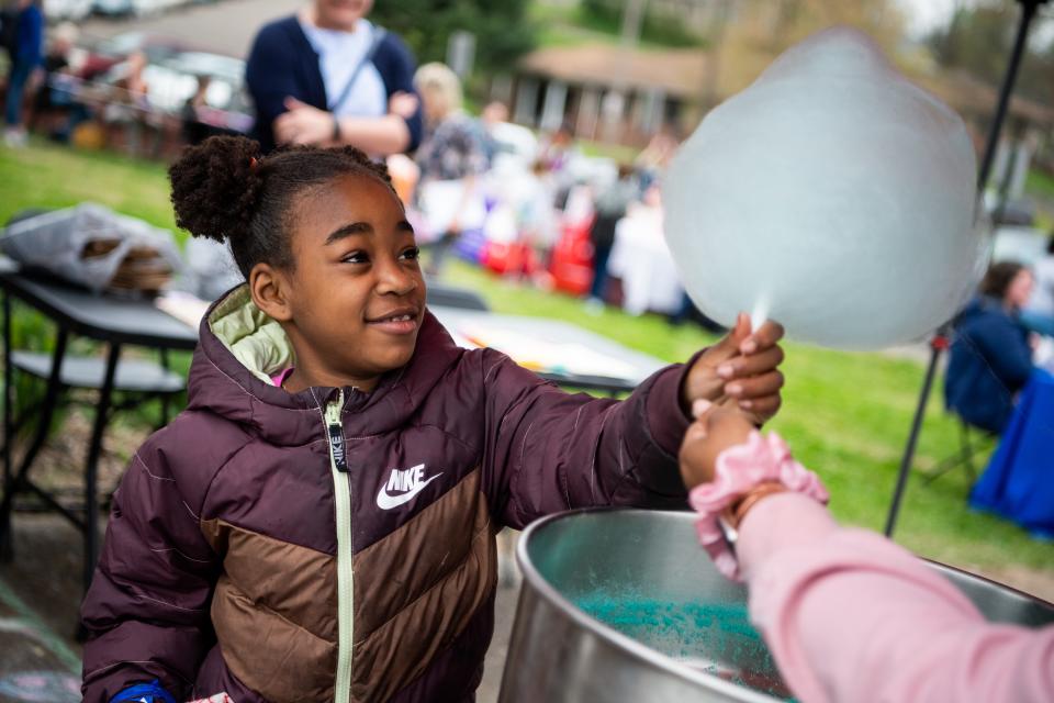 A young child smile as she's handed cotton candy during an Easter egg hunt hosted by Knoxville's Community Development Corporation at Knoxville's Western Heights community held on Monday, April 3, 2023.