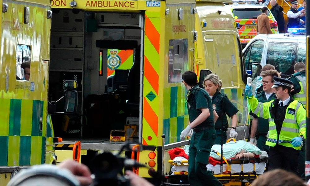 Paramedics load a victim into the back of an ambulance.