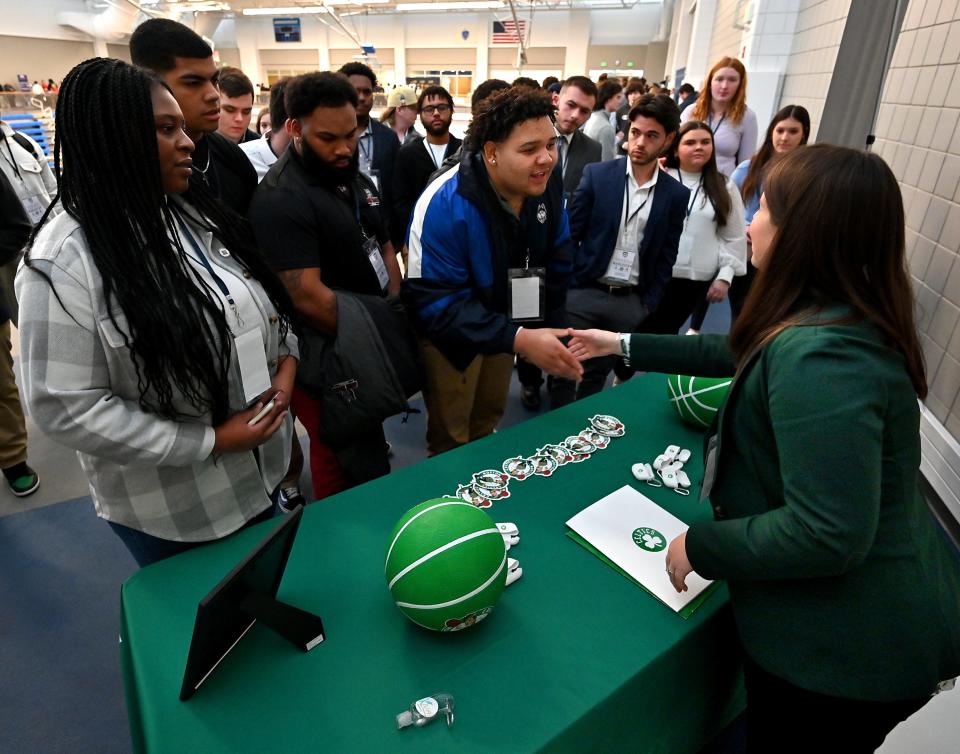 Anna Maria College digital marketing freshman Emiliano Pastorino of Fitchburg, center, shakes hands with Katie Sullivan, inside sales manager for the Boston Celtics, during the Worcester Sports Management Summit at Worcester State University.