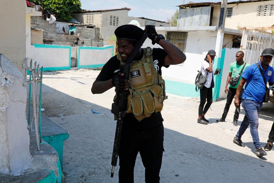 Jimmy Chérizier, a former elite police officer known as Barbecue who leads the G9 and Family gang, adjusts his weapon as he speaks to journalists in the Delmas 6 neighborhood of Port-au-Prince, Haiti, Monday, March 11, 2024. (AP Photo/Odelyn Joseph)