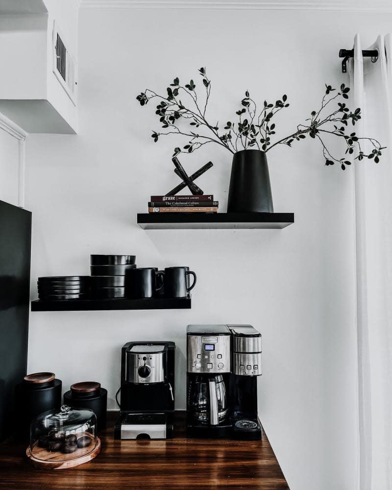 Coffee bar area with black shelves, black appliances, black mugs, etc